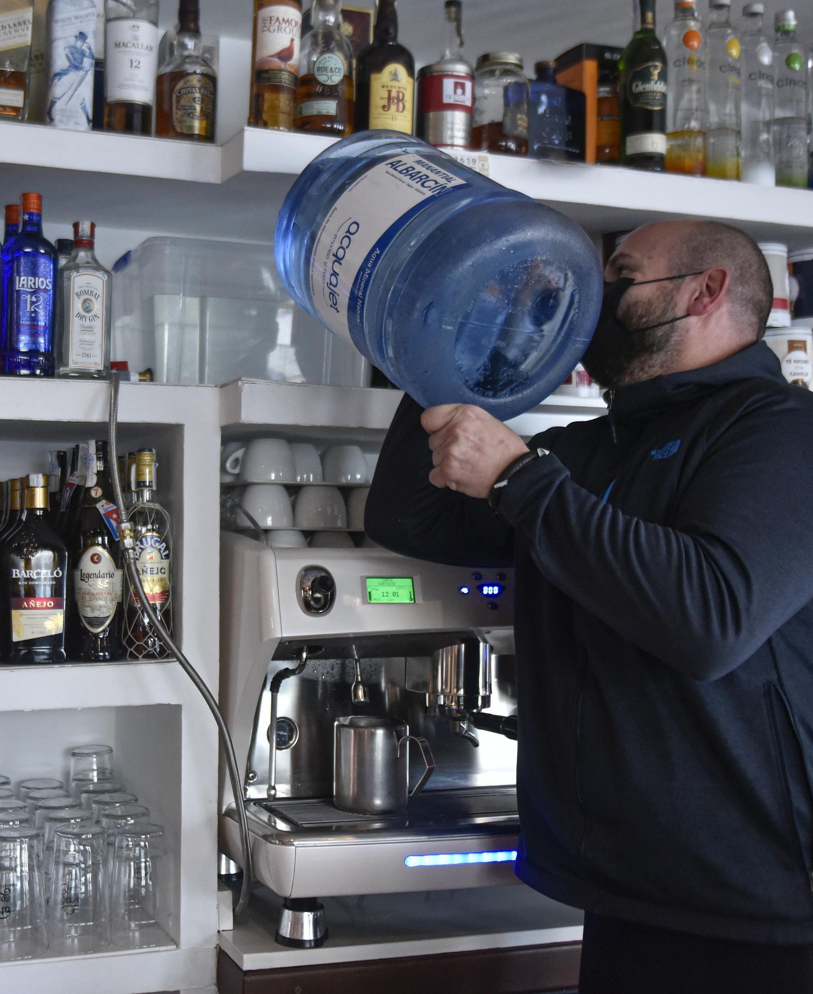 El propietario de un bar prepara la cafetera con agua de un camión cisterna.