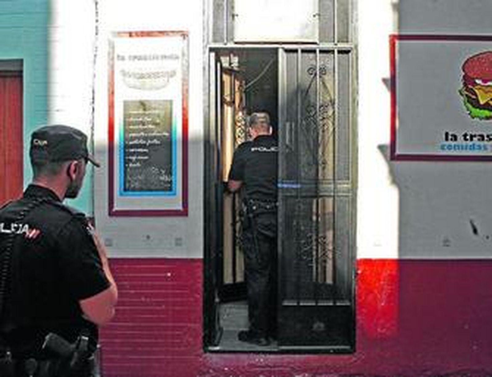 Dos policías examinan la puerta de la hamburguesería cuando fue cortado el precinto.