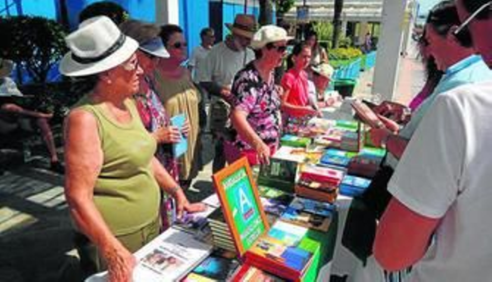 Vecinos y turistas ojeando los libros del stand instalado en La Carihuela.