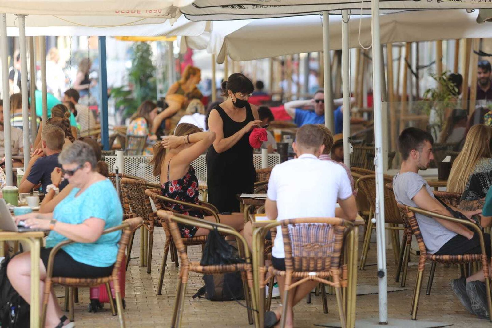 Una camarera toma nota a una pareja en una terraza de Málaga.