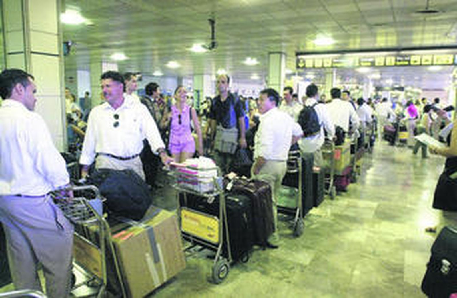 Un grupo de pasajeros espera ante un mostrador de Madrid-Barajas para facturar su equipaje.