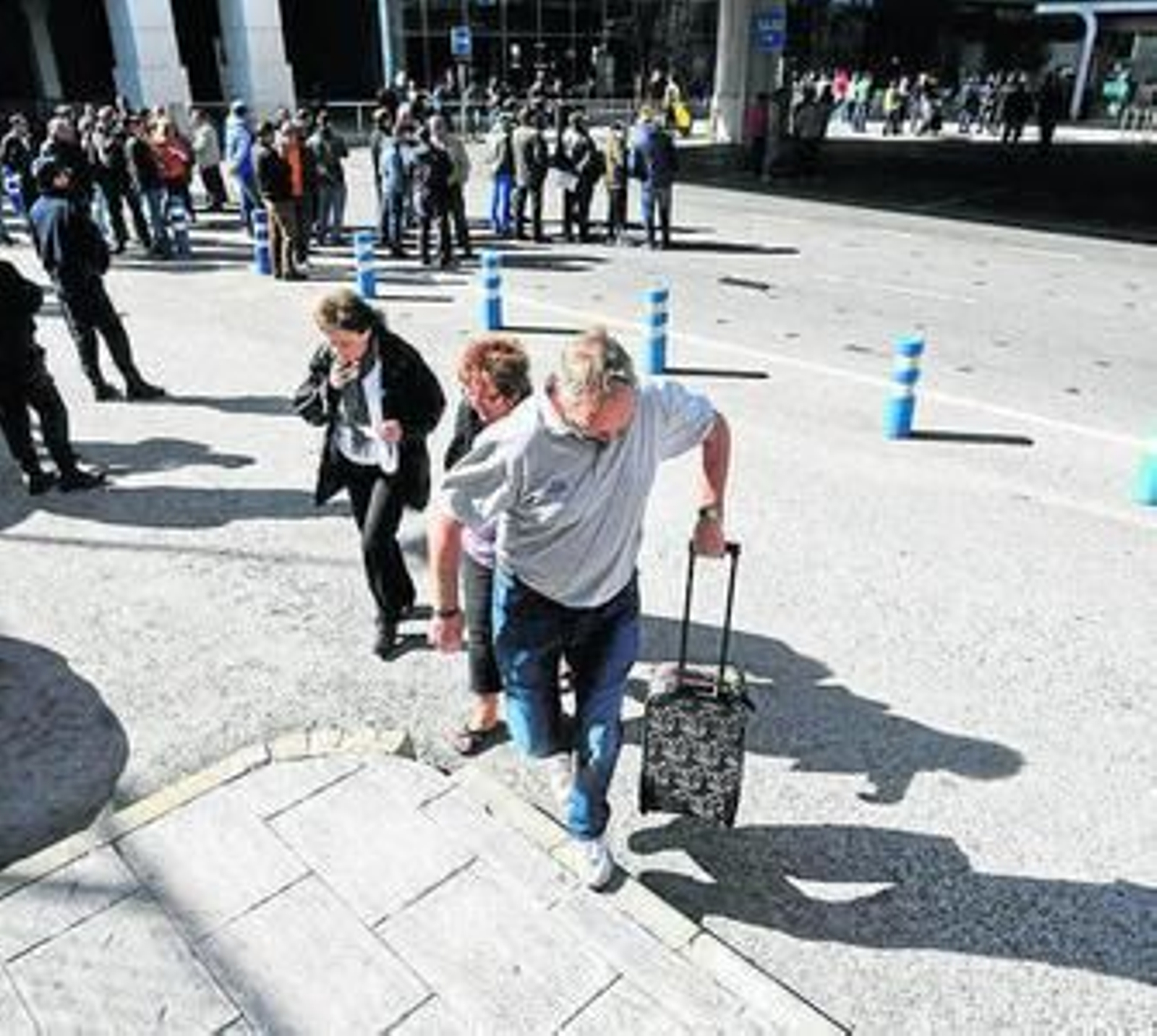 Pasajeros llevan sus maletas ante la ausencia de taxis en el aeropuerto.