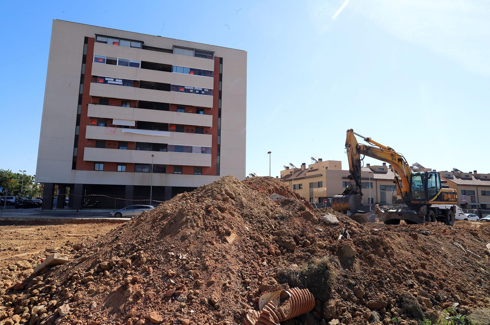 Bloque de viviendas con carteles de protesta junto a la parcela ya en obras.