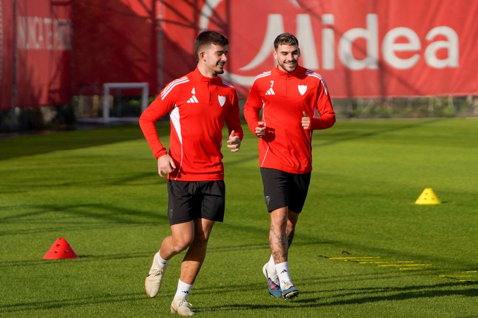 Kike Salas sonríe junto a Isaac en un entrenamiento del Sevilla.