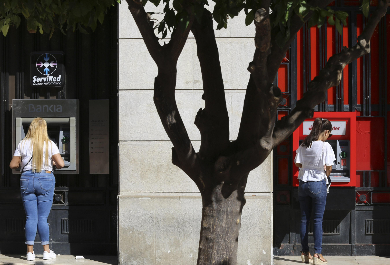 Clientes de banca usando los cajeros automáticos.