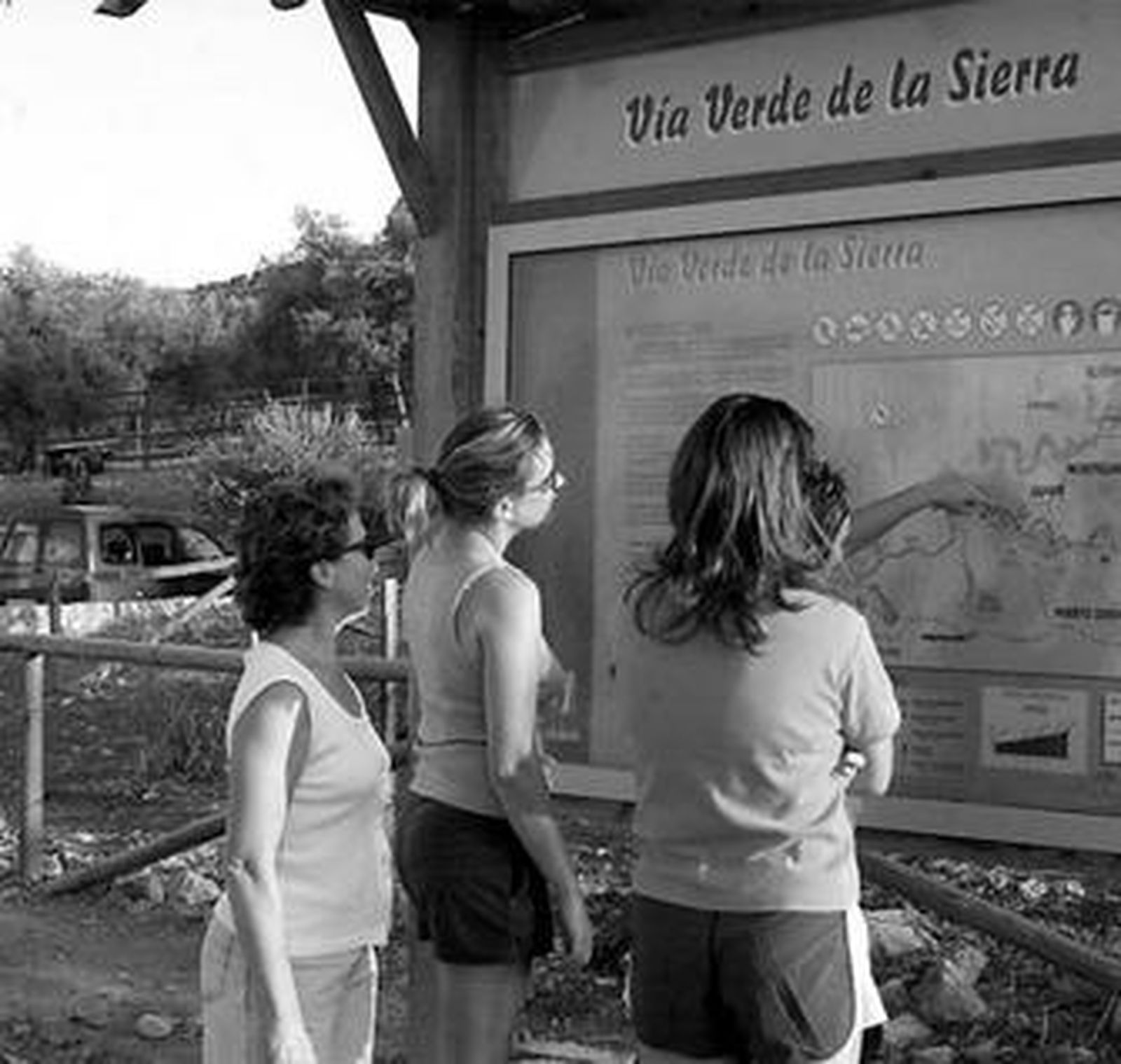 Varias mujeres, mirando los carteles de la Vía Verde de la Sierra.