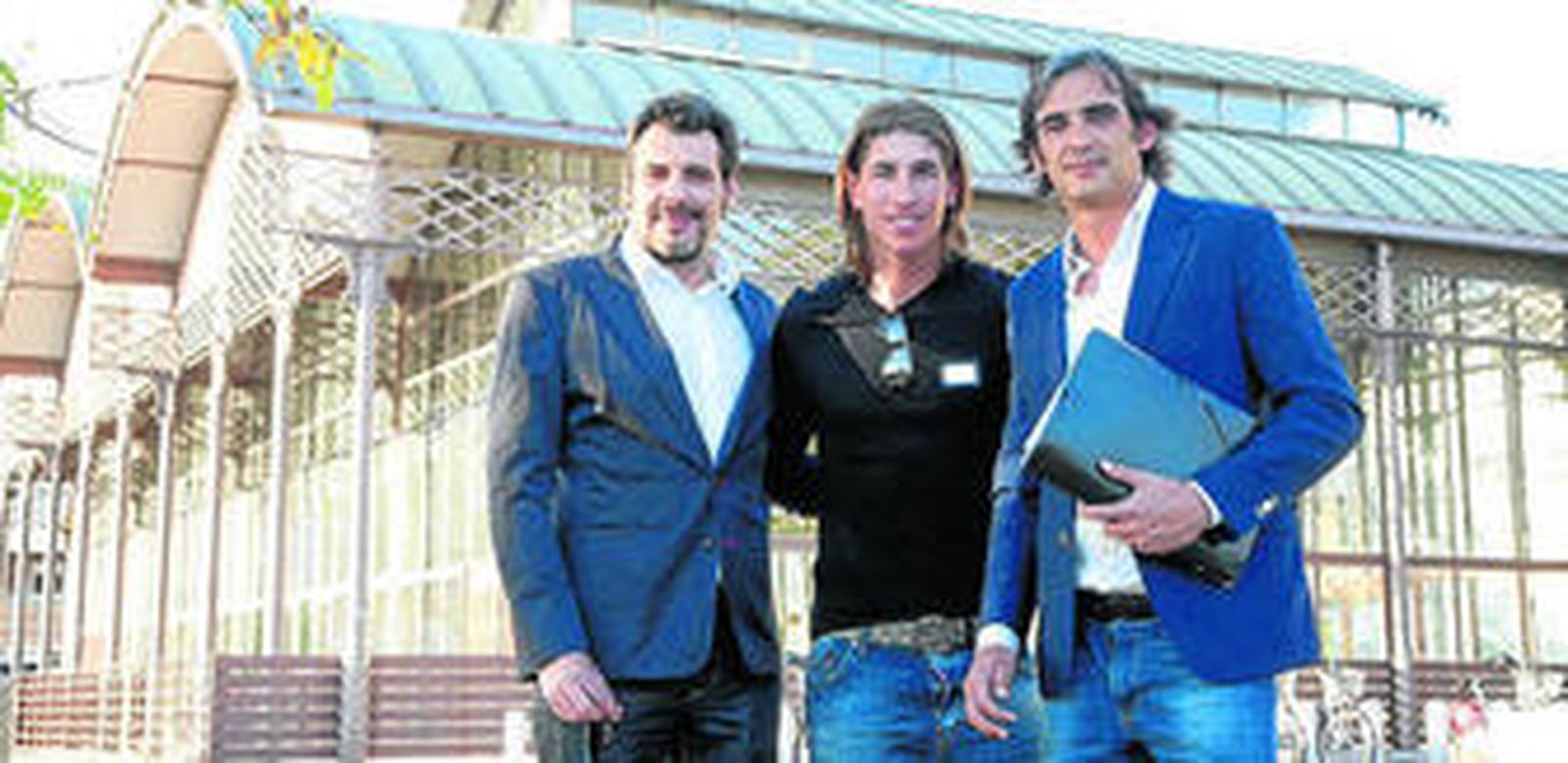 Los hermanos Óscar y Juanjo Vega posan con el futbolista Sergio Ramos, de la misma UTE, junto a las naves.