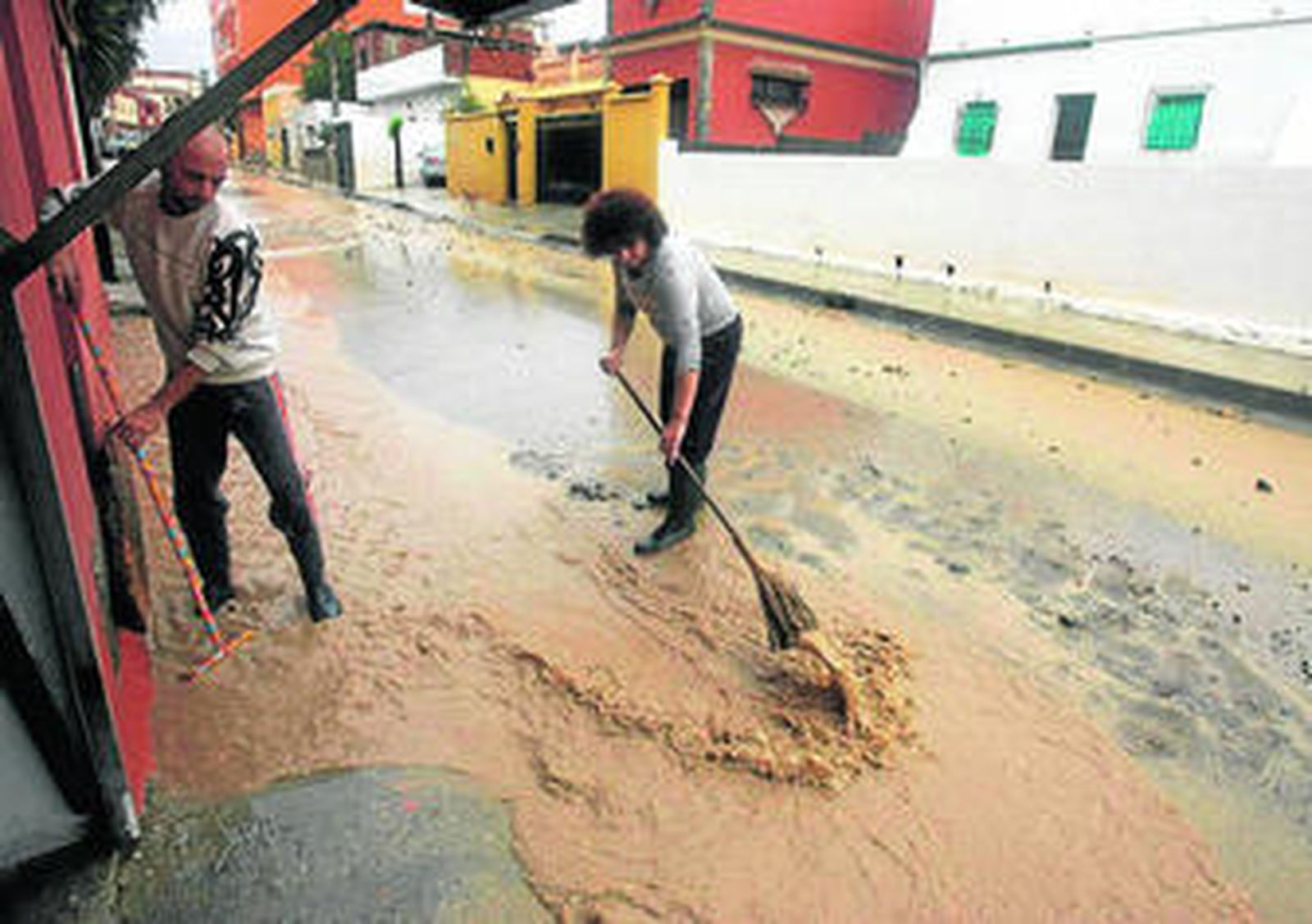 Vecinos del barrio de El Cobre, en Algeciras, achican agua de sus viviendas.