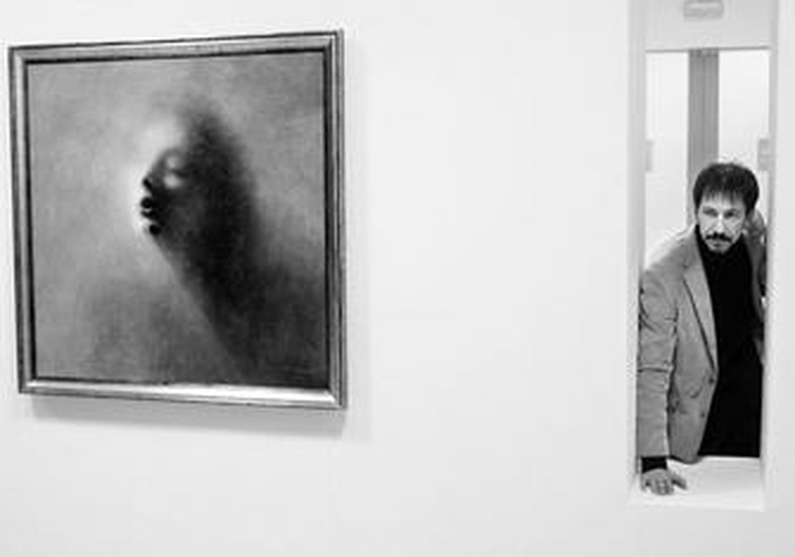 El pintor posa en junto a una de sus obras.