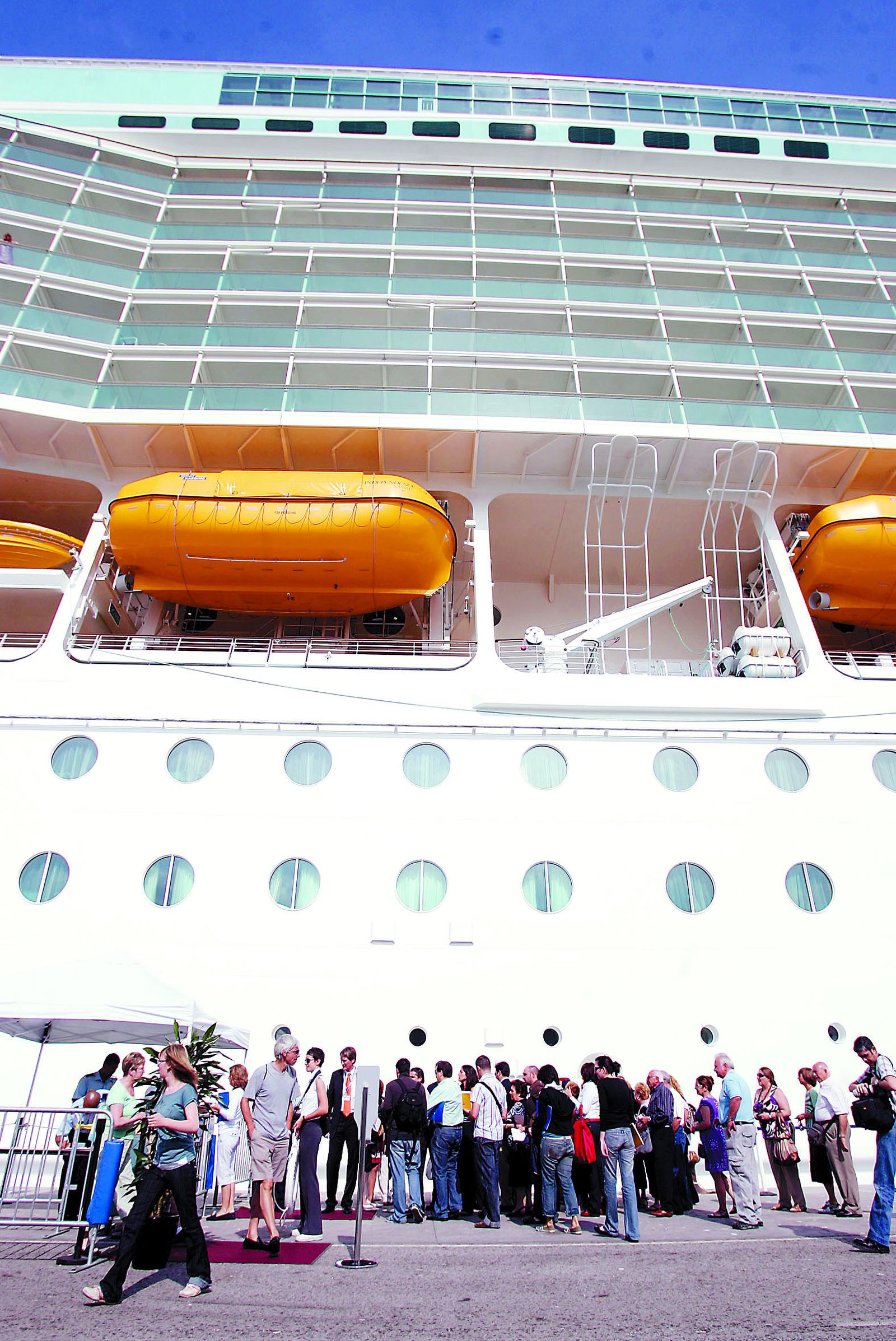 Viajeros junto a un buque de crucero en el puerto de Málaga.