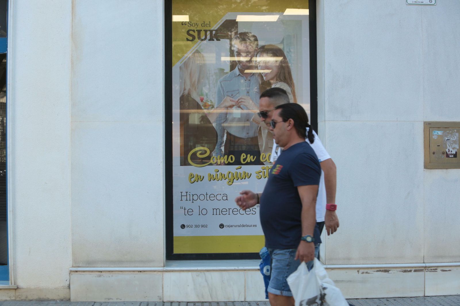 Dos personas pasan por un cartel con una oferta de hipoteca