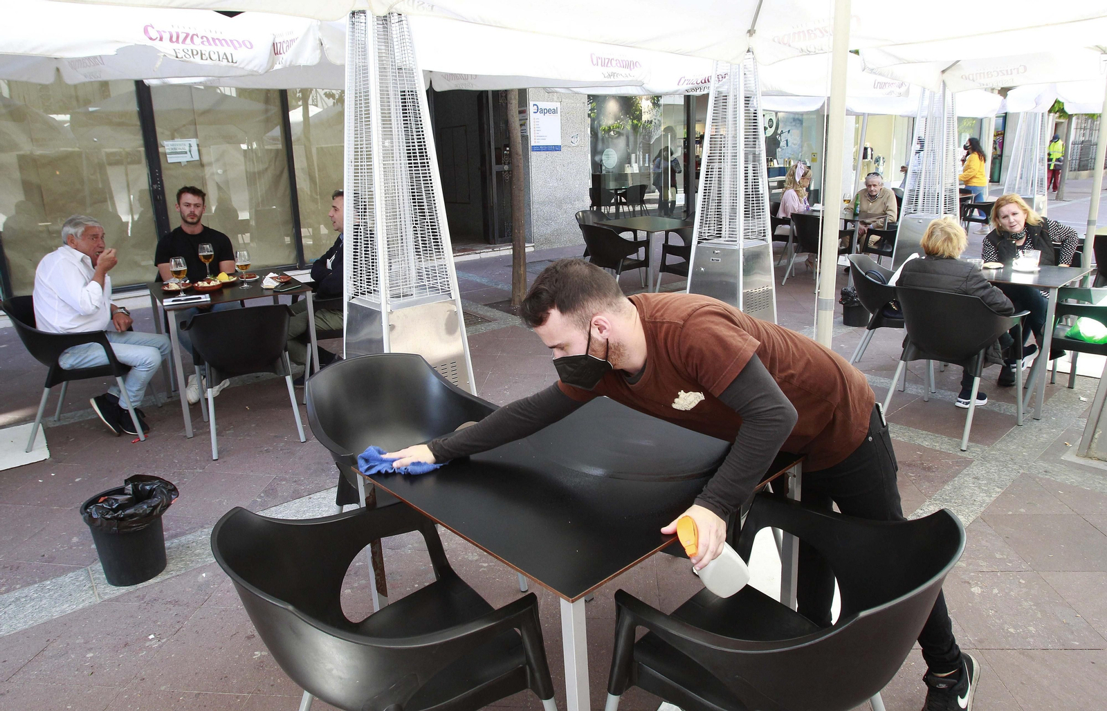 Un camarero desinfecta una mesa en una terraza de Algeciras.