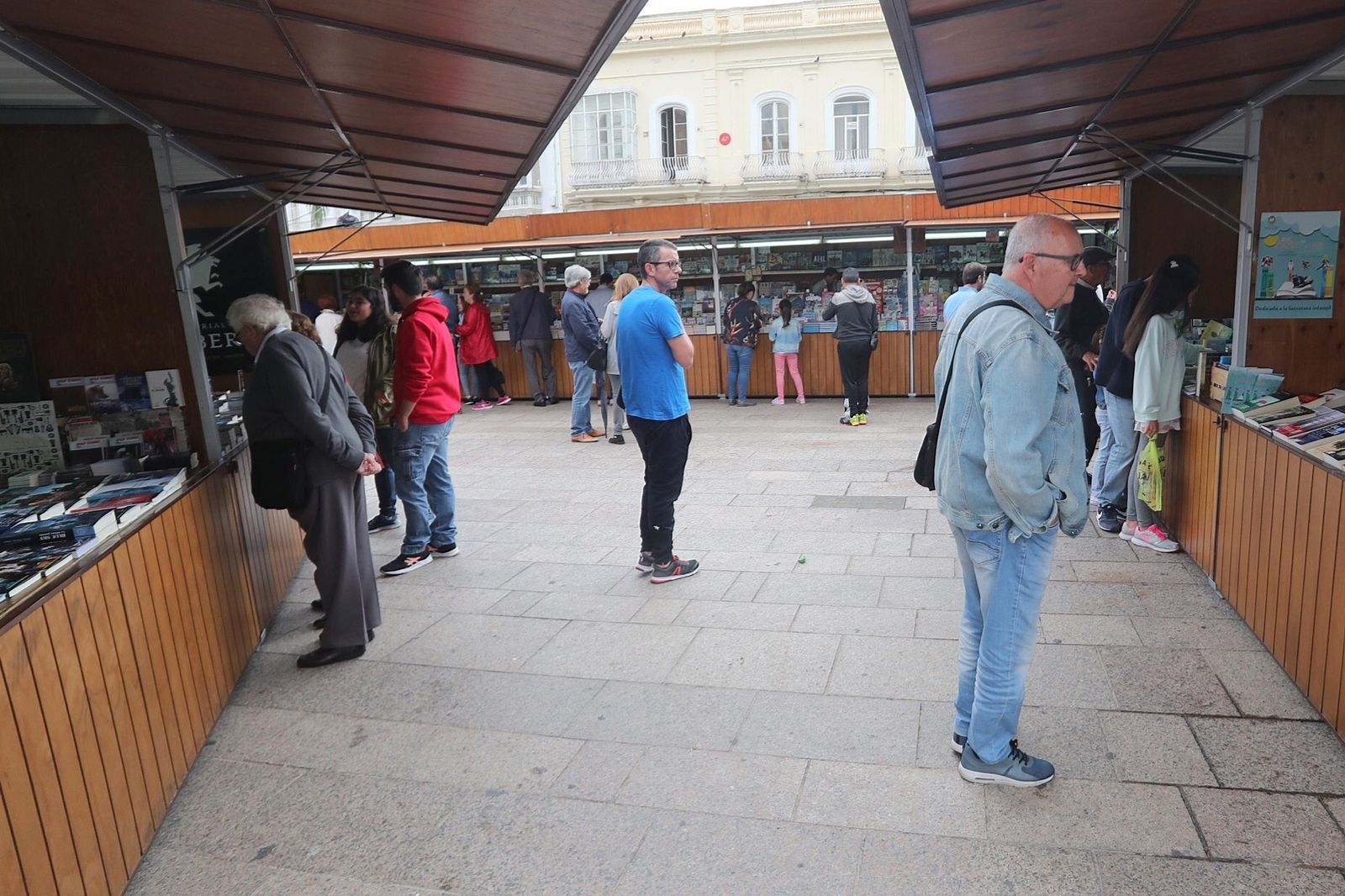 Lectores a la búsqueda de títulos entre los expositores colocados en la plaza de la Iglesia.