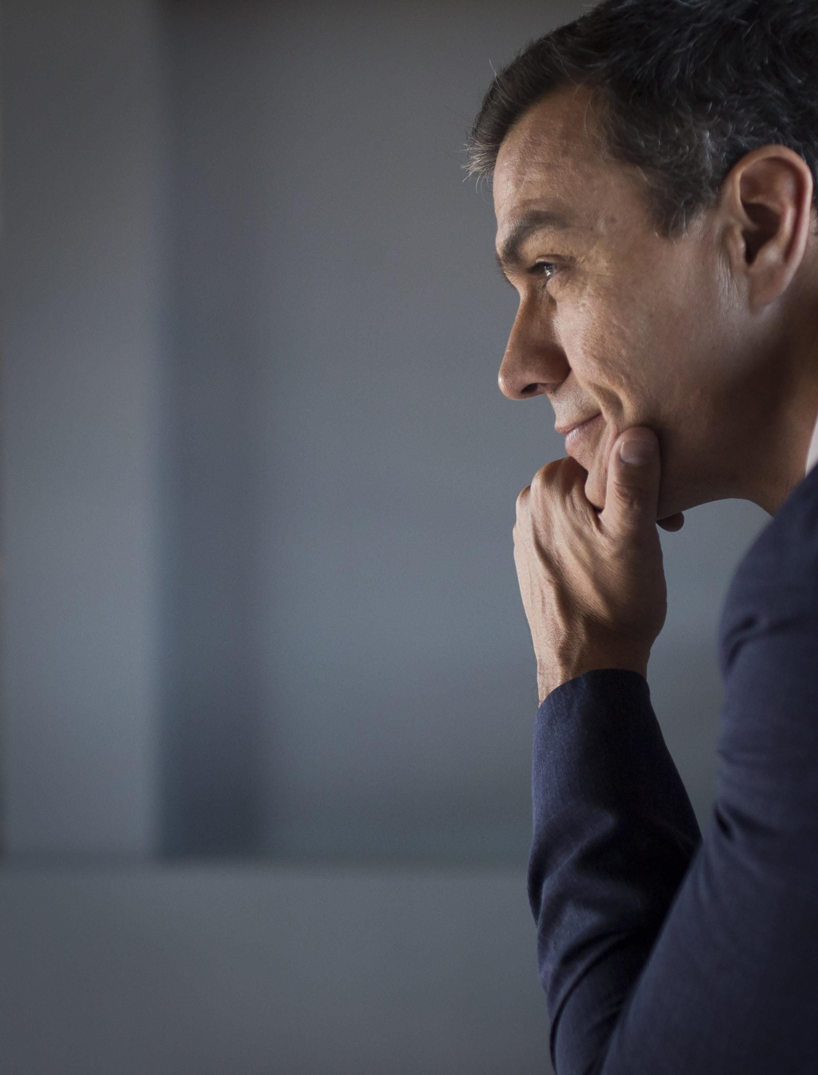 Sánchez escucha sonriendo.