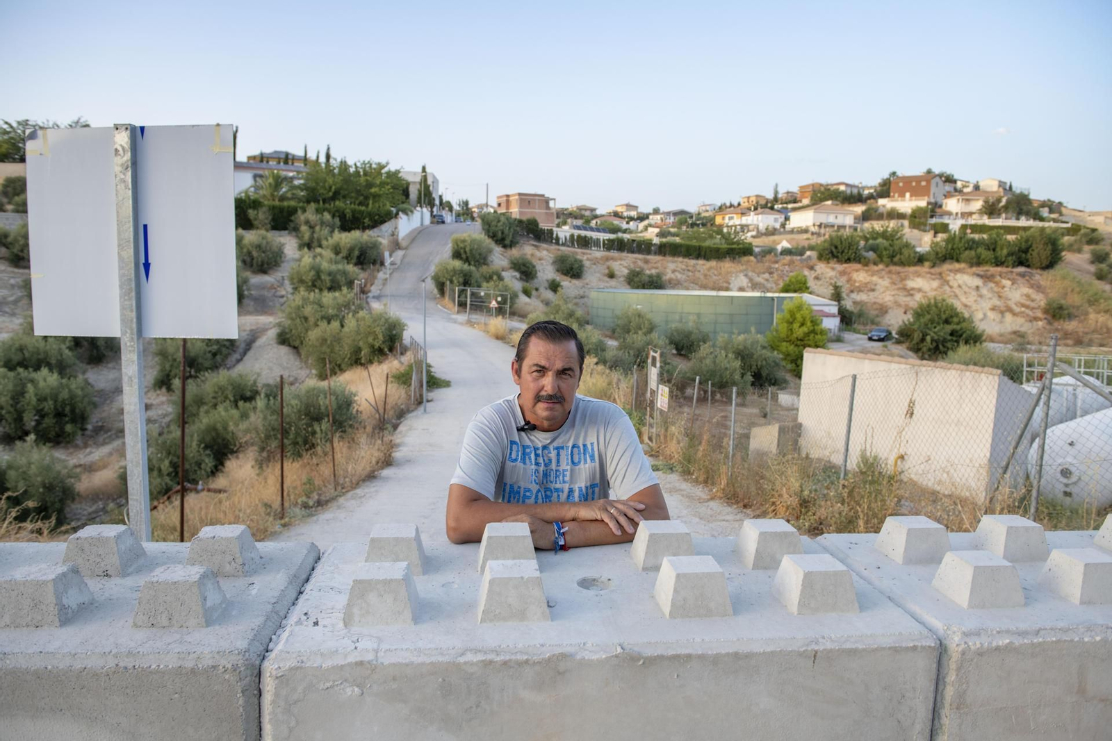 Francisco Molina, representante de los vecinos de la urbanización La Manseguilla (al fondo) en Jaén capital, que posa apoyado en el muro de hormigón instalado por el Ayuntamiento de La Guardia.