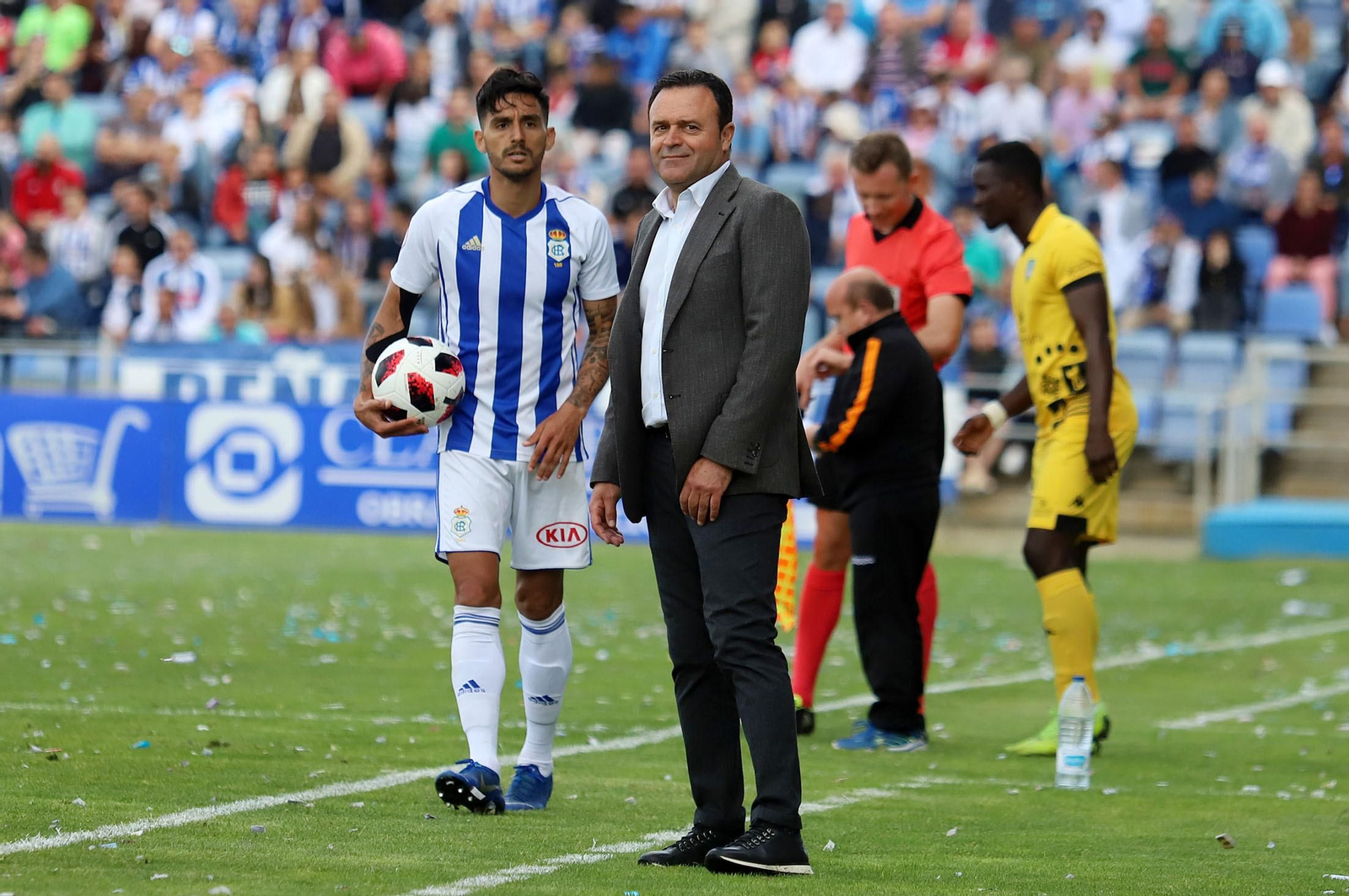 José María Salmerón sonríe desde el área técnica en un partido, con Pablo Andrade cerca.