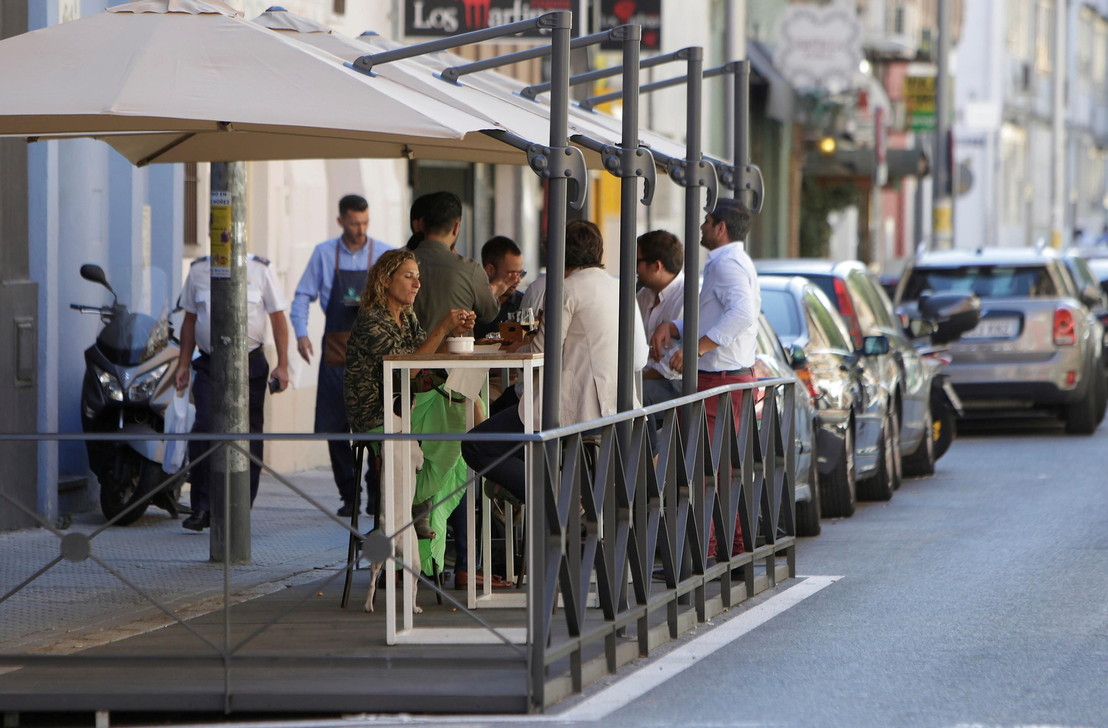 Varios clientes en el velador de un bar instalado en un aparcamiento.