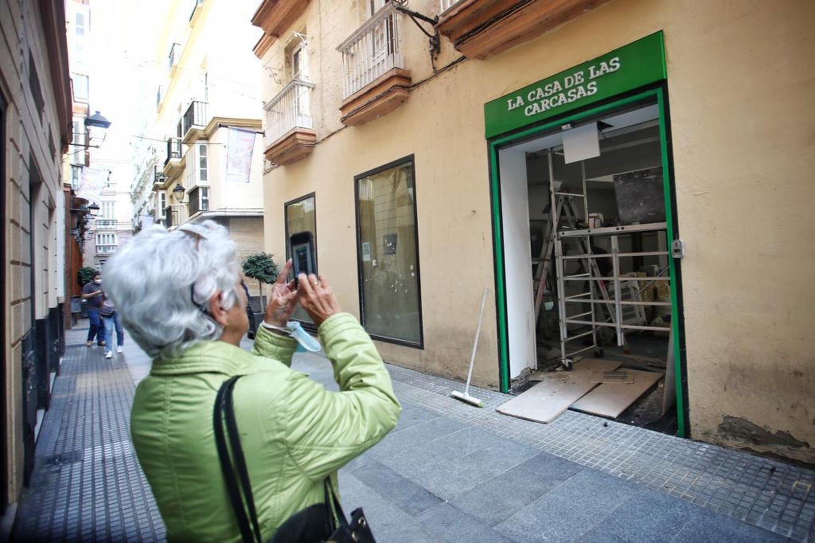 Una mujer fotografía la fachada de la futura tienda La Casa de las Carcasas, en la calle Columela.