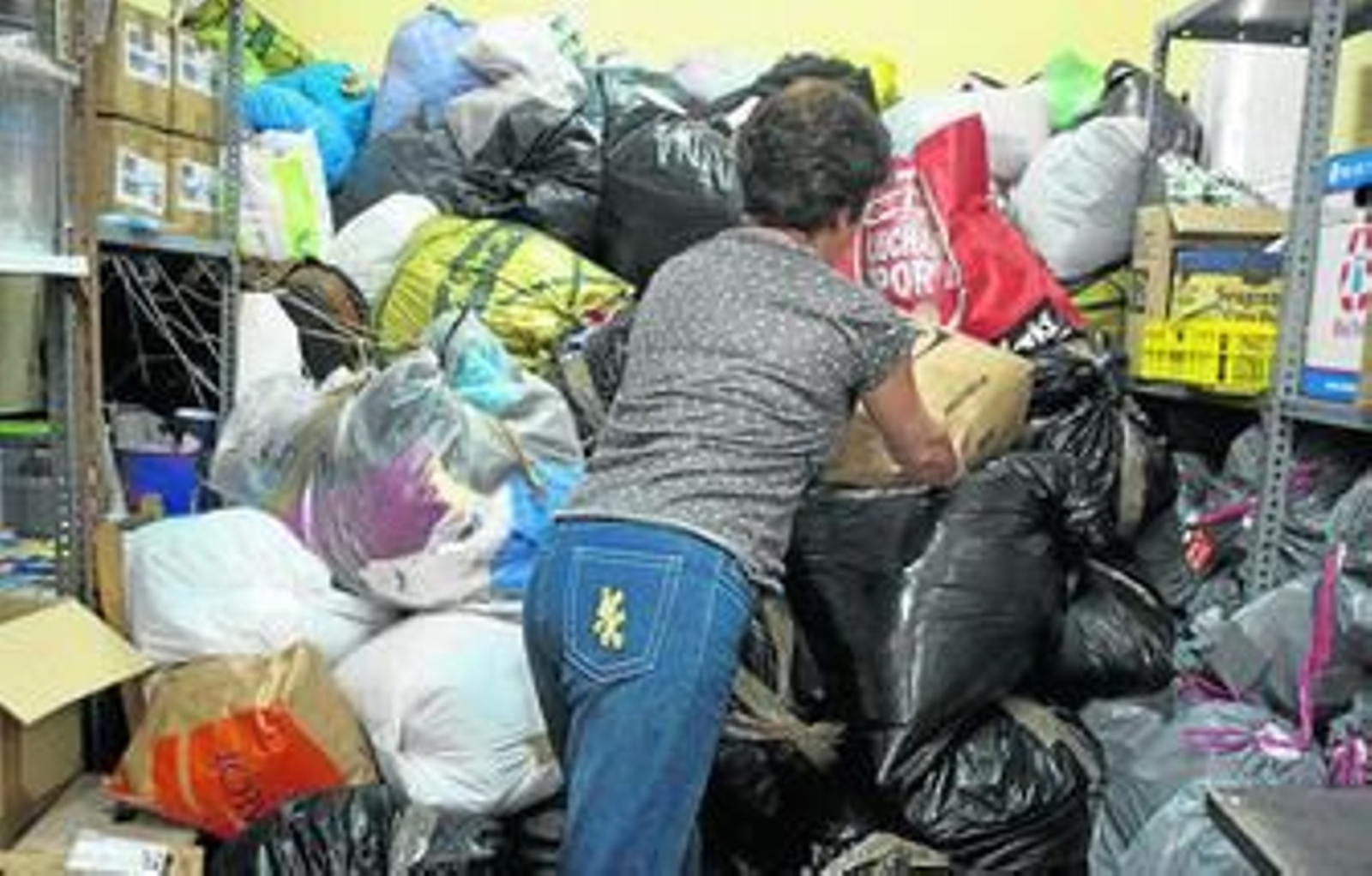 Una voluntaria coloca bolsas de ropa donadas en la sede de Madre Coraje en Cádiz.