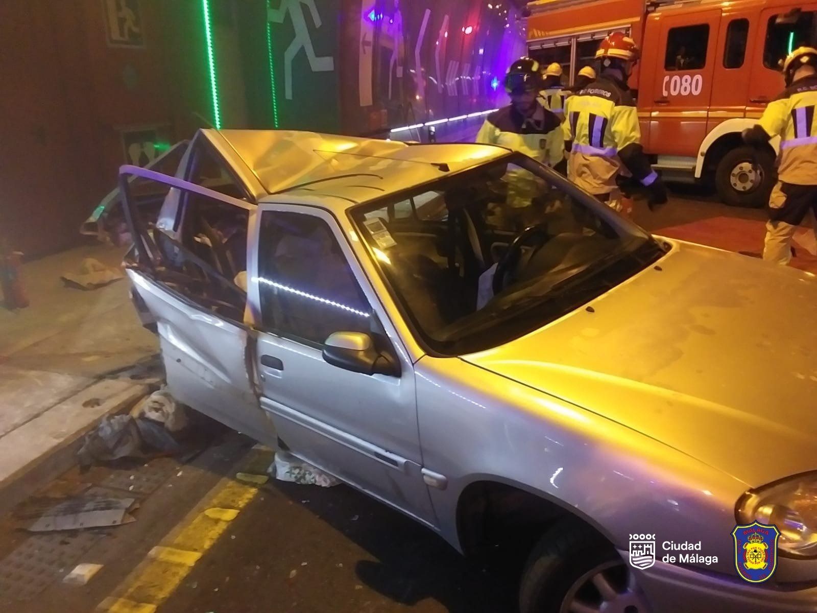 Bomberos junto al coche siniestrado en el túnel.