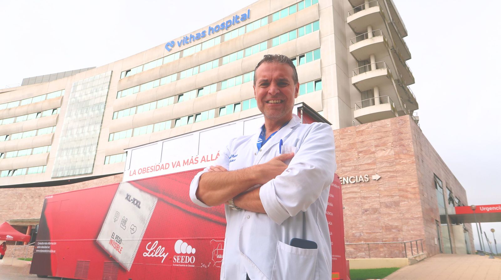 El doctor Cristóbal Morales, endocrino de Vithas Sevilla junto a al camión de 'El peso de lo invisible' en las instalaciones del hospital.