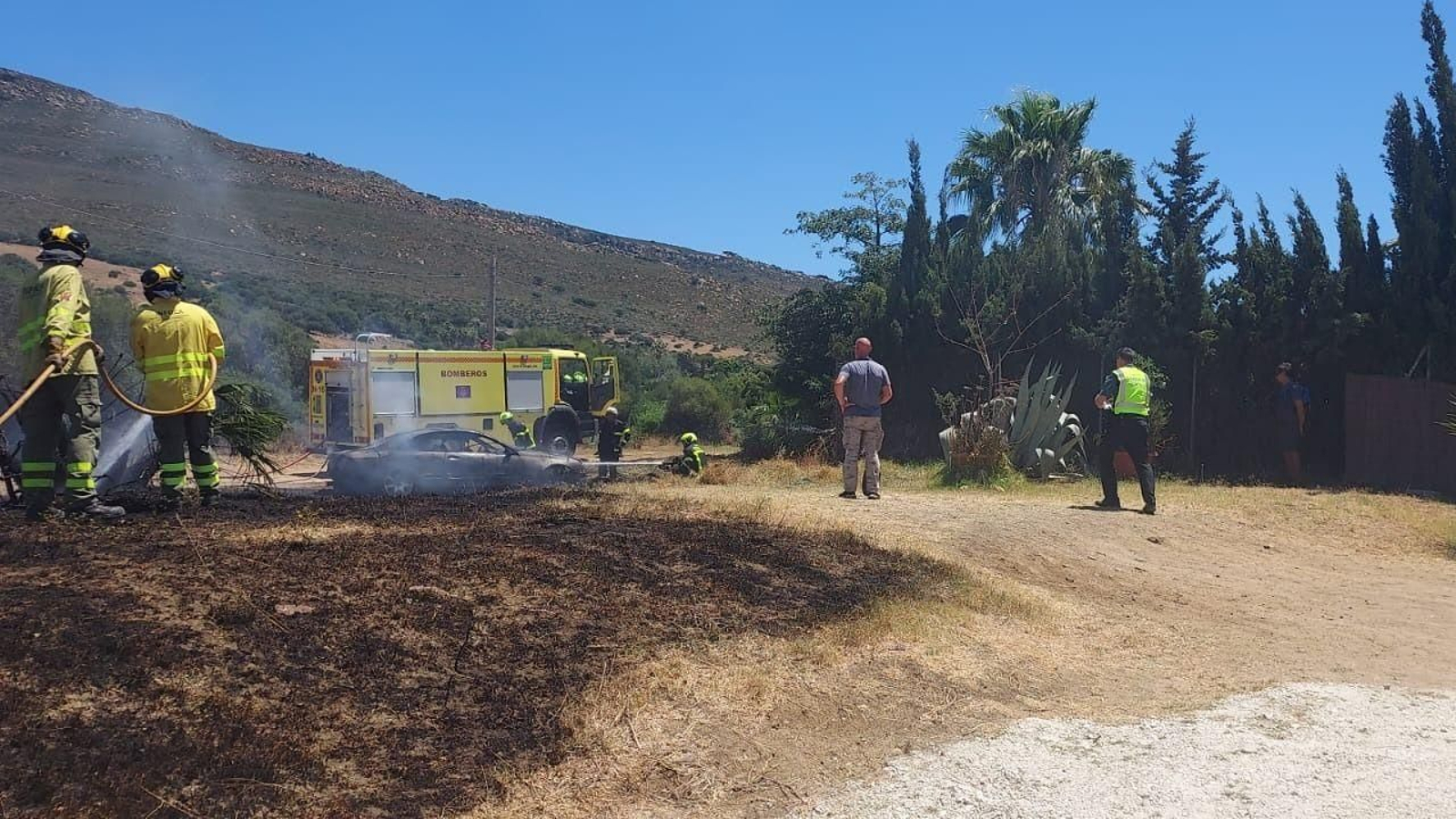 Los bomberos actúan en el vehículo calcinado en Tarifa.