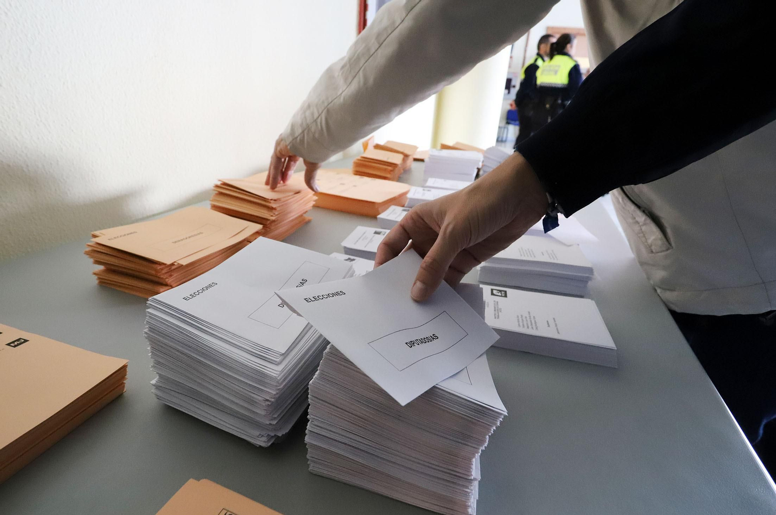 Un votante coge una papeleta en la mesa electoral.
