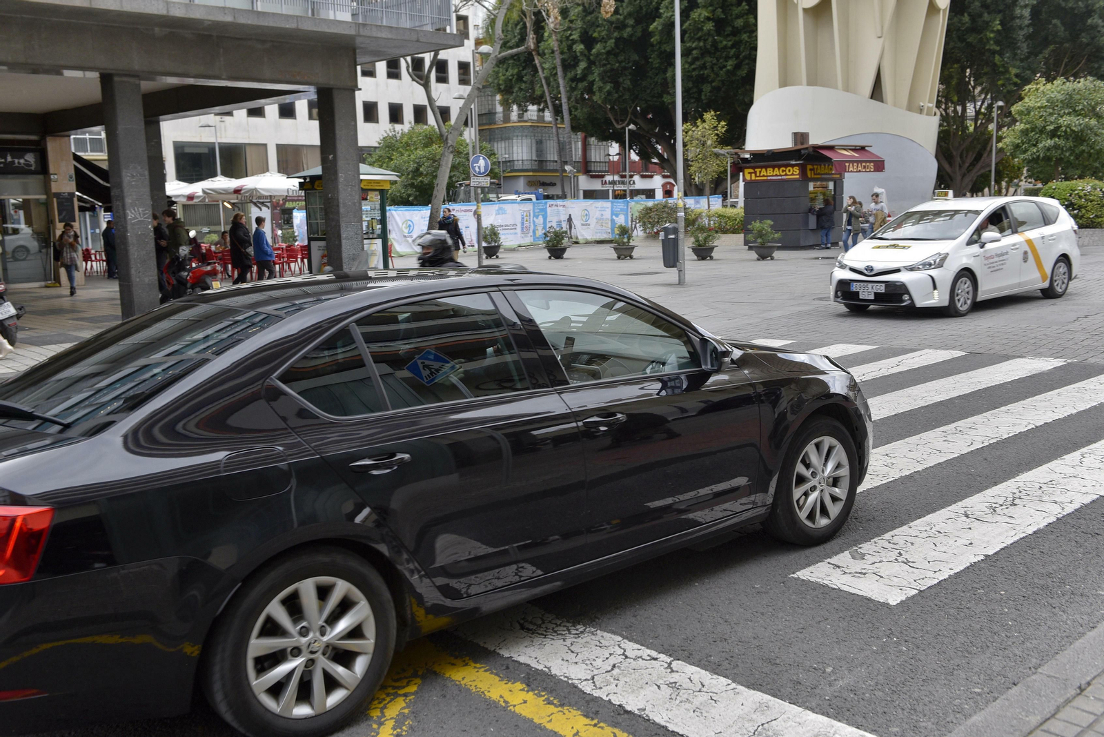 Un VTC y un taxi, a punto de cruzarse en una calle de Sevilla.