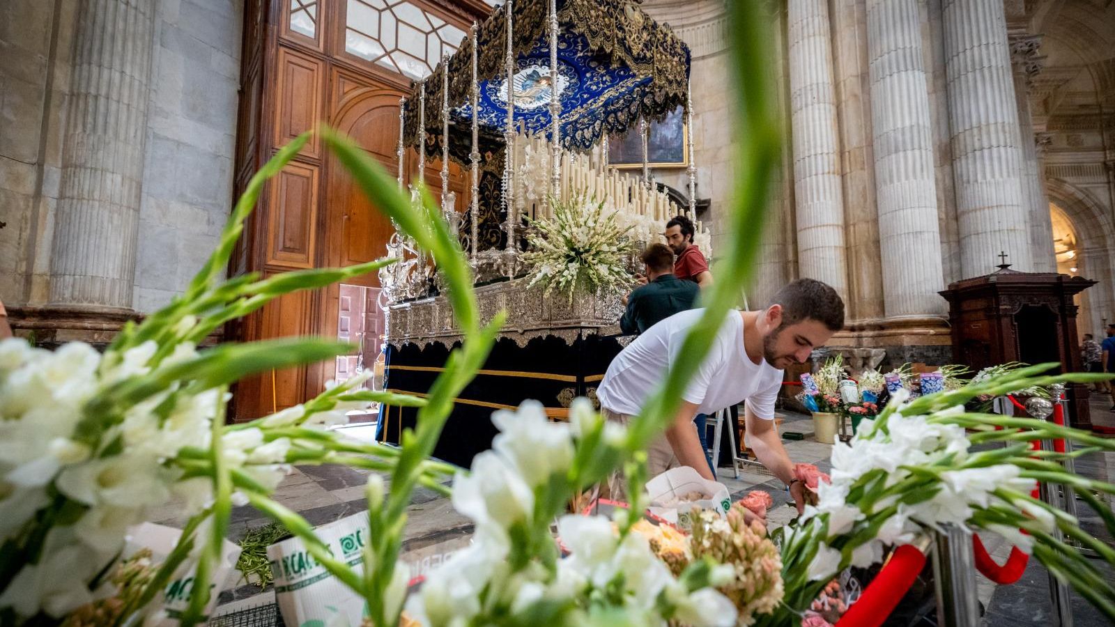 Cofrades de La Palma preparan el exorno floral para el paso de palio de la Virgen de las Penas.