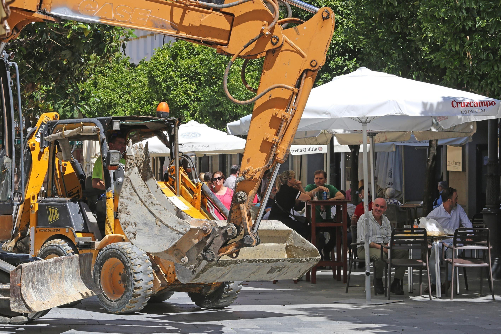 Una excavadora circula junto a las terrazas de los bares en el centro.