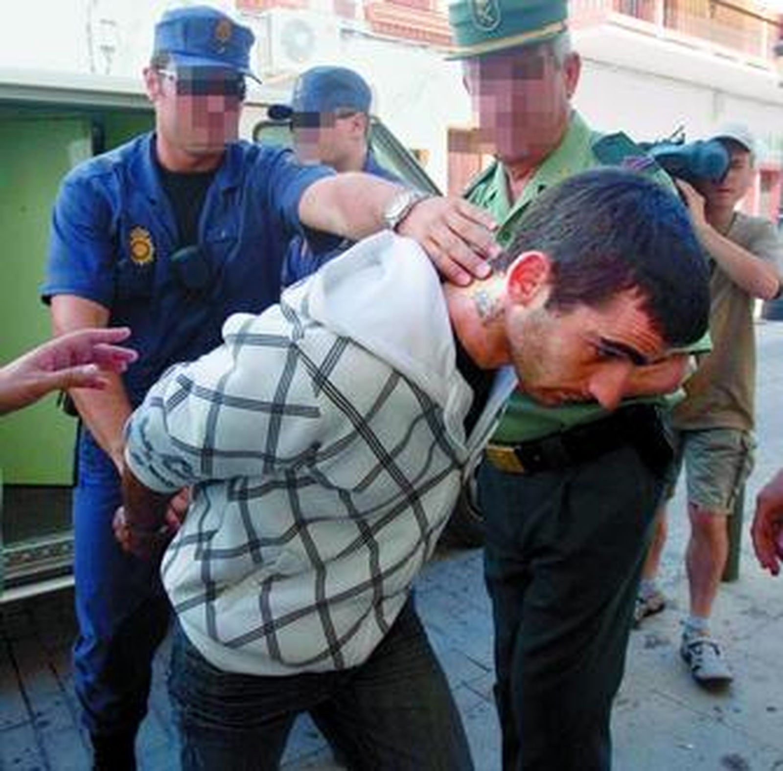 Dos agentes custodian a uno de los nueve detenidos, J.A.G.R., al juzgado de La Palma del Condado, ayer.