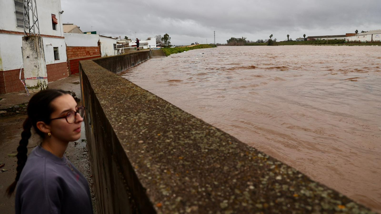 Una joven se asoma a la tapia que separa el callejón del Churre del arroyo del mismo nombre, cuya crecida es espectacular.