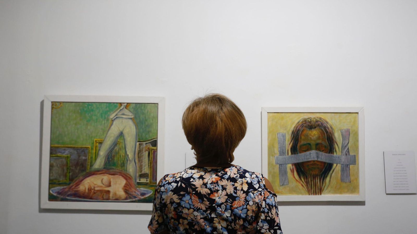 Una mujer observa varios cuadros de la muestra.