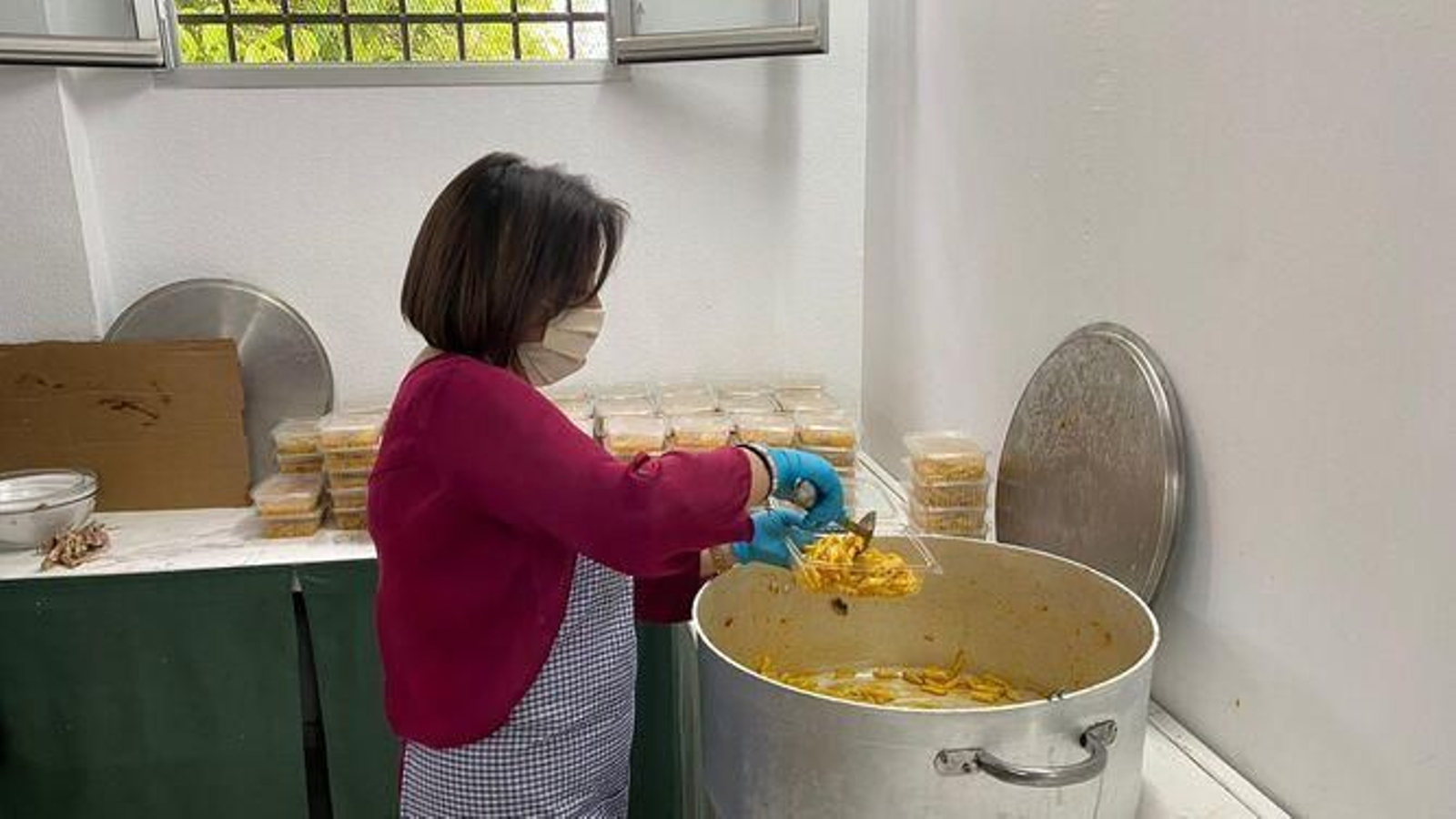 Una voluntaria de Cáritas elabora comida para repartir entre familias necesitadas.