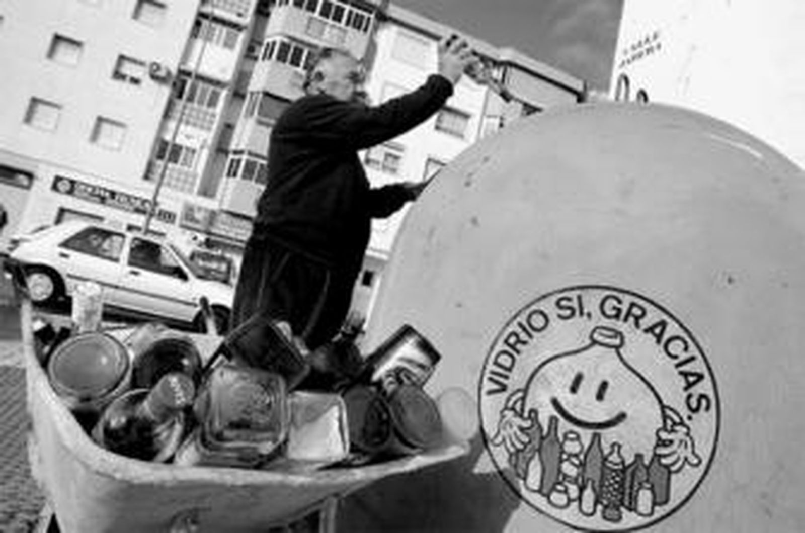 Un hombre recicla botellas de vidrio en un contenedor de Vélez-Málaga.
