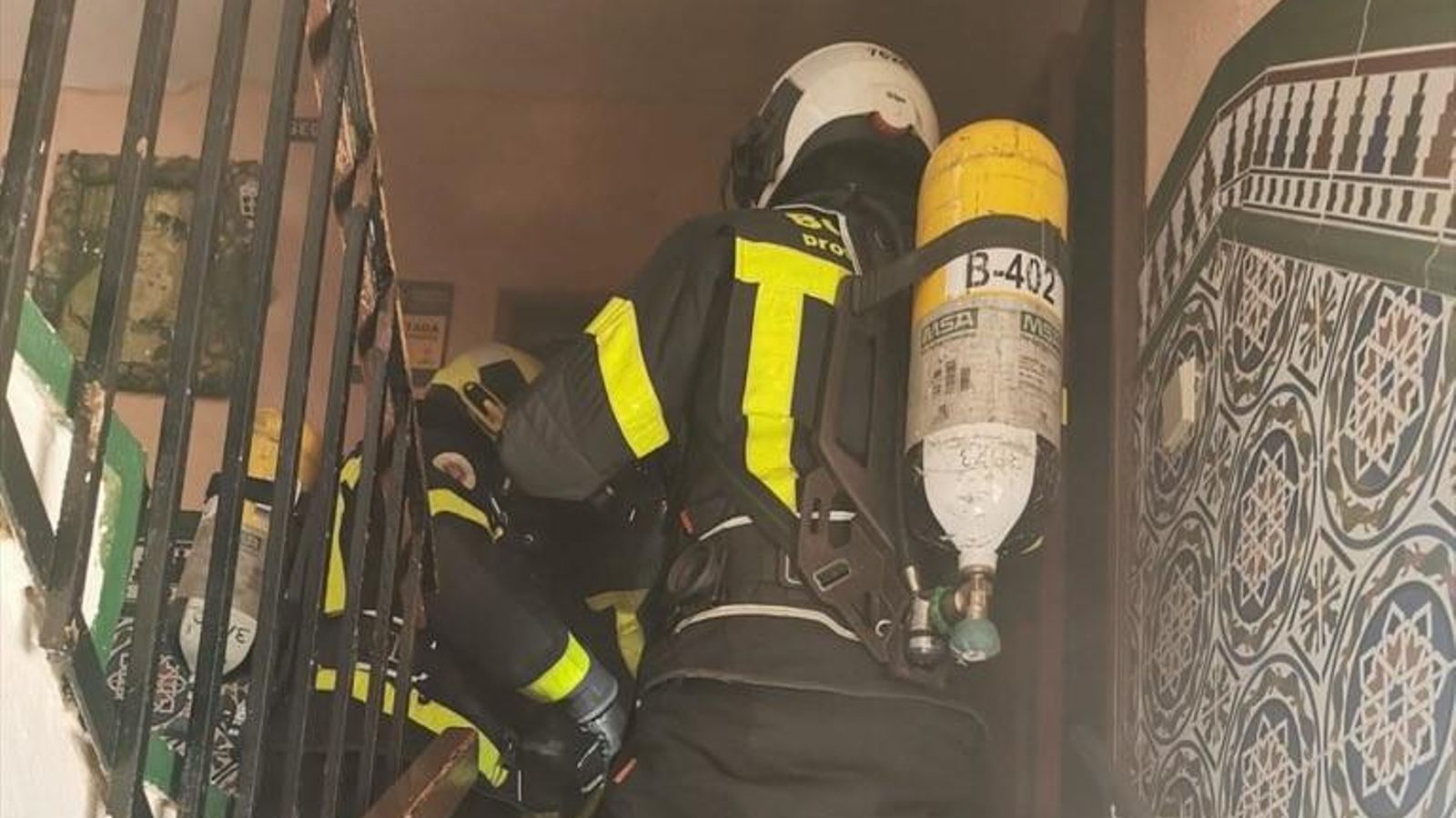 Los bomberos en el rellano de la escalera a punto de entrar en el piso incendiado en Jerez