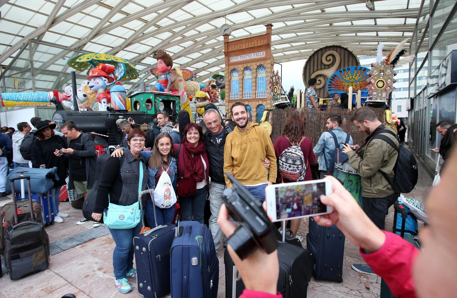 Componentes del coro de Luis Rivero a su llegada a Oviedo se fotografían delante de la carroza exornada con la portada del Teatro Falla.