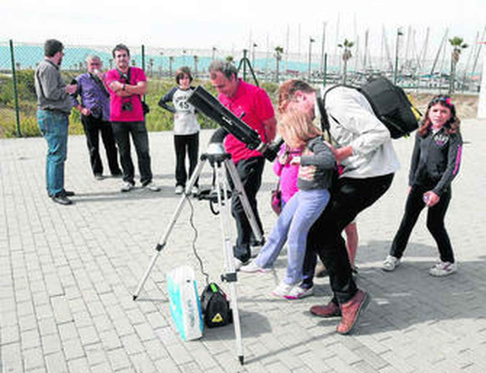 Un hombre aúpa a una pequeña hasta el visor del telescopio para ver el eclipse solar, ayer en La Línea.