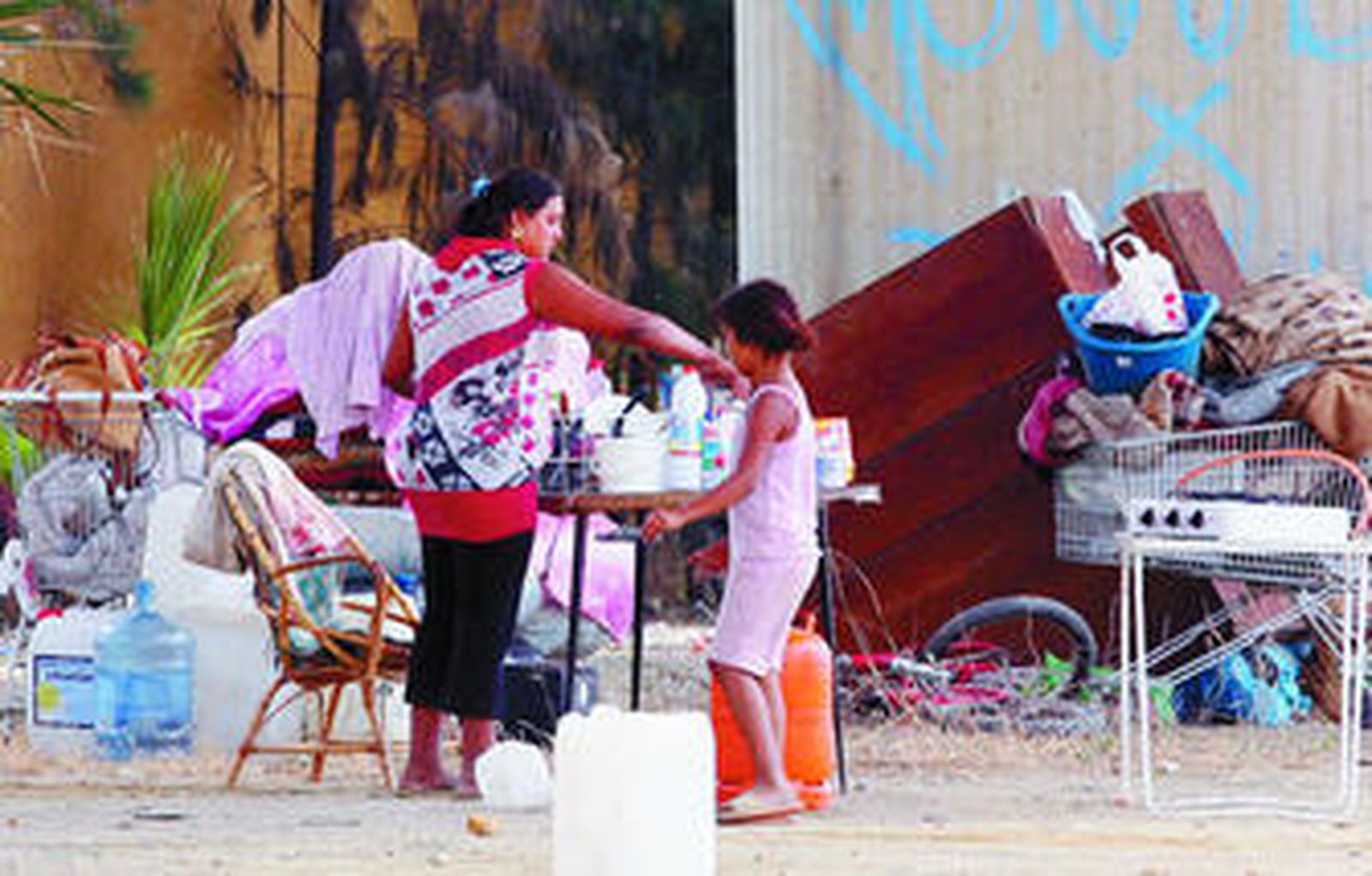 Una madre con su hija preparan el desayuno en los terrenos bajo el puente de San Juan.