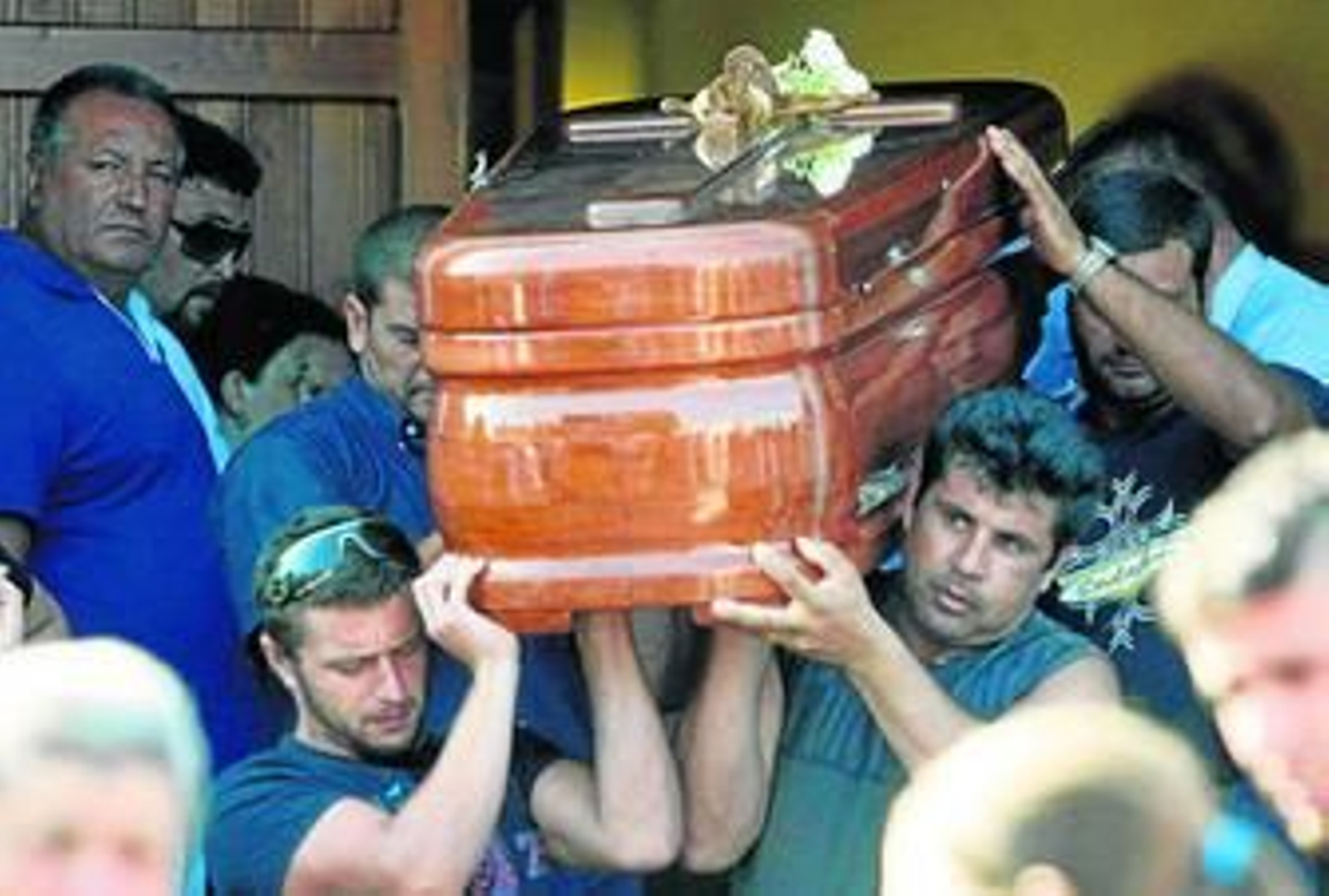 Los restos mortales de los fallecidos salen a hombros de la familia mientras la gente aplaude en la calle.
