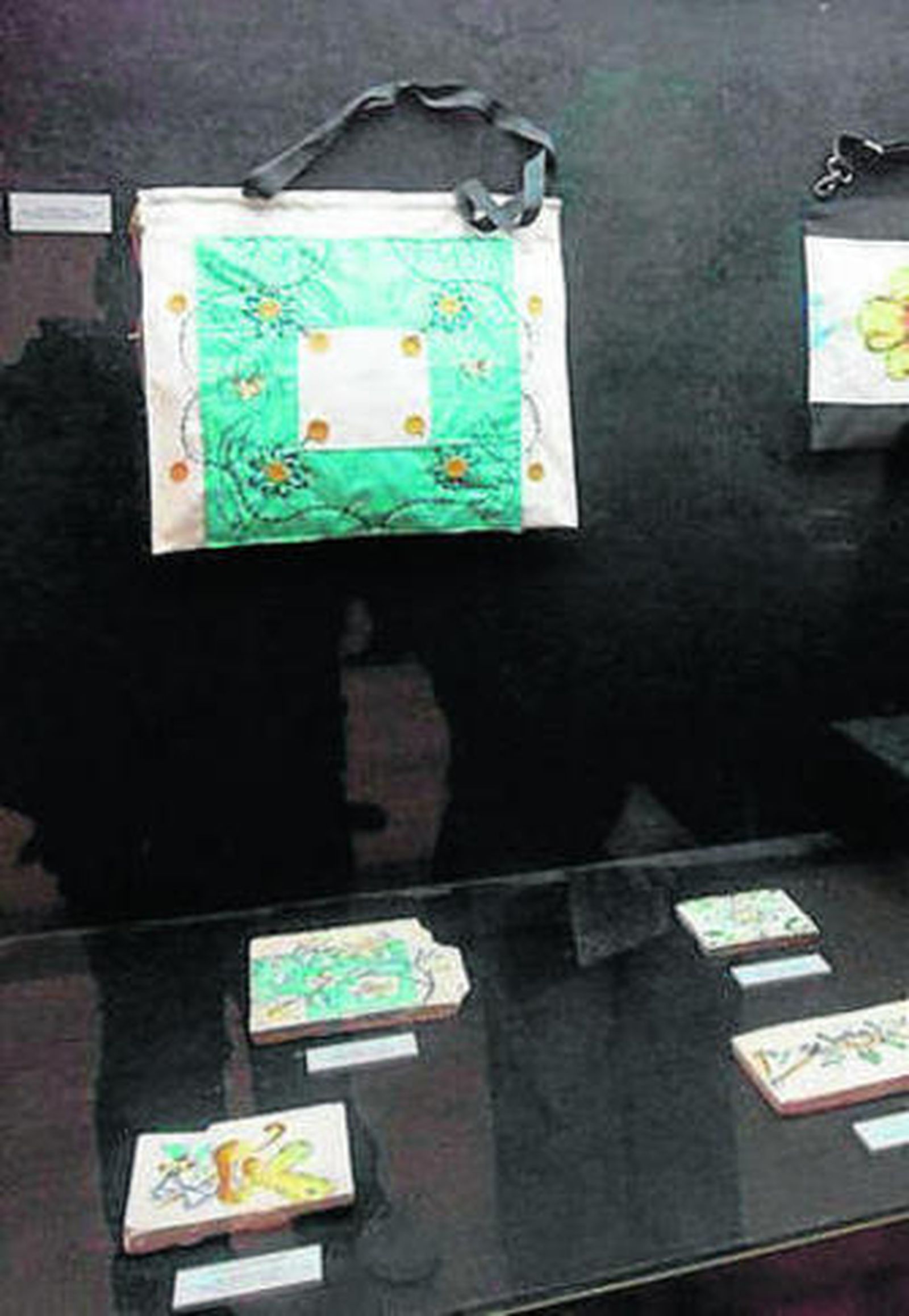 La artista Amanda Alonso, delante de uno de sus bolsos y el azulejo que inspiró su diseño.