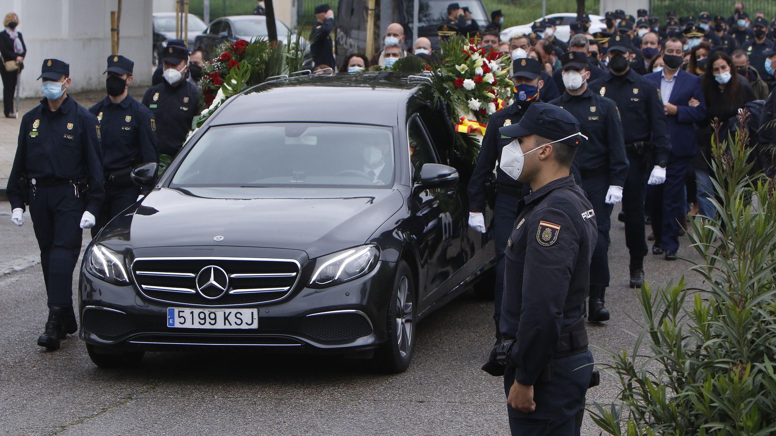 La comitiva acompaña al coche  fúnebre con los restos del policía nacional fallecido en Sevilla.