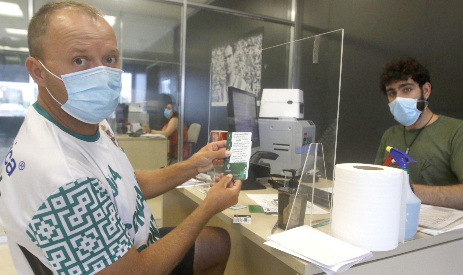 Un seguidor enseña sus carnés de esta temporada.