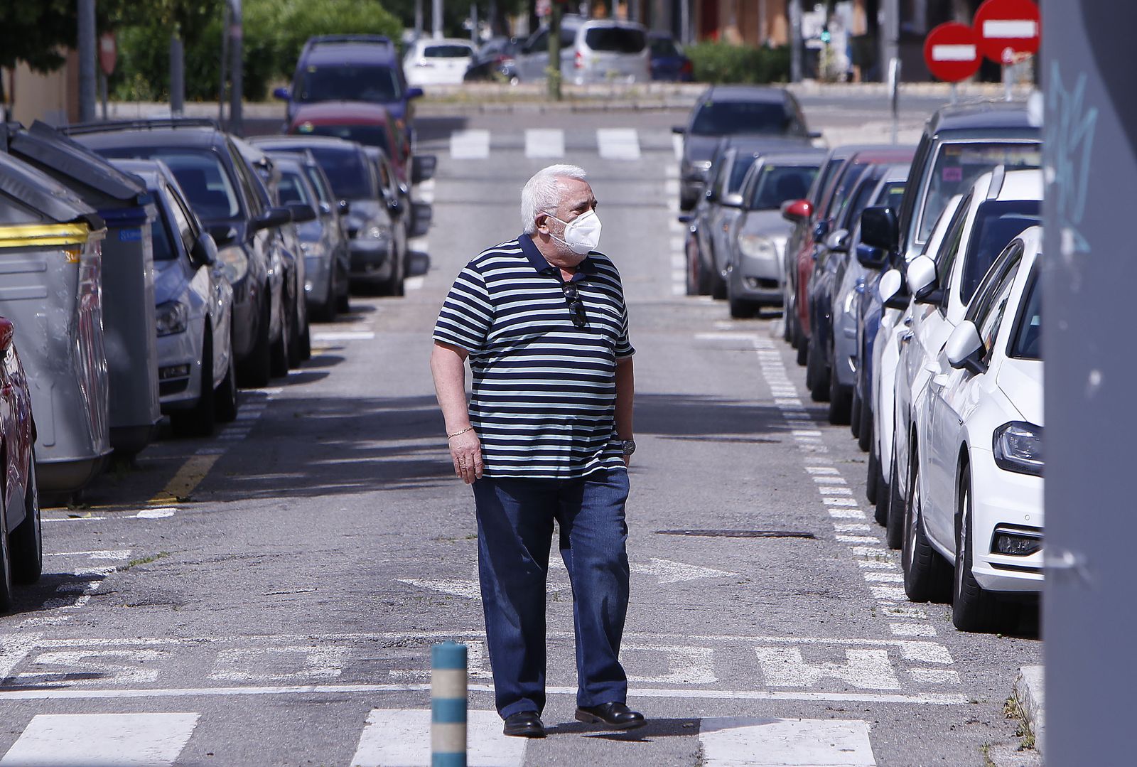Una personas atraviesa, con mascarillas, un paso de peatones.