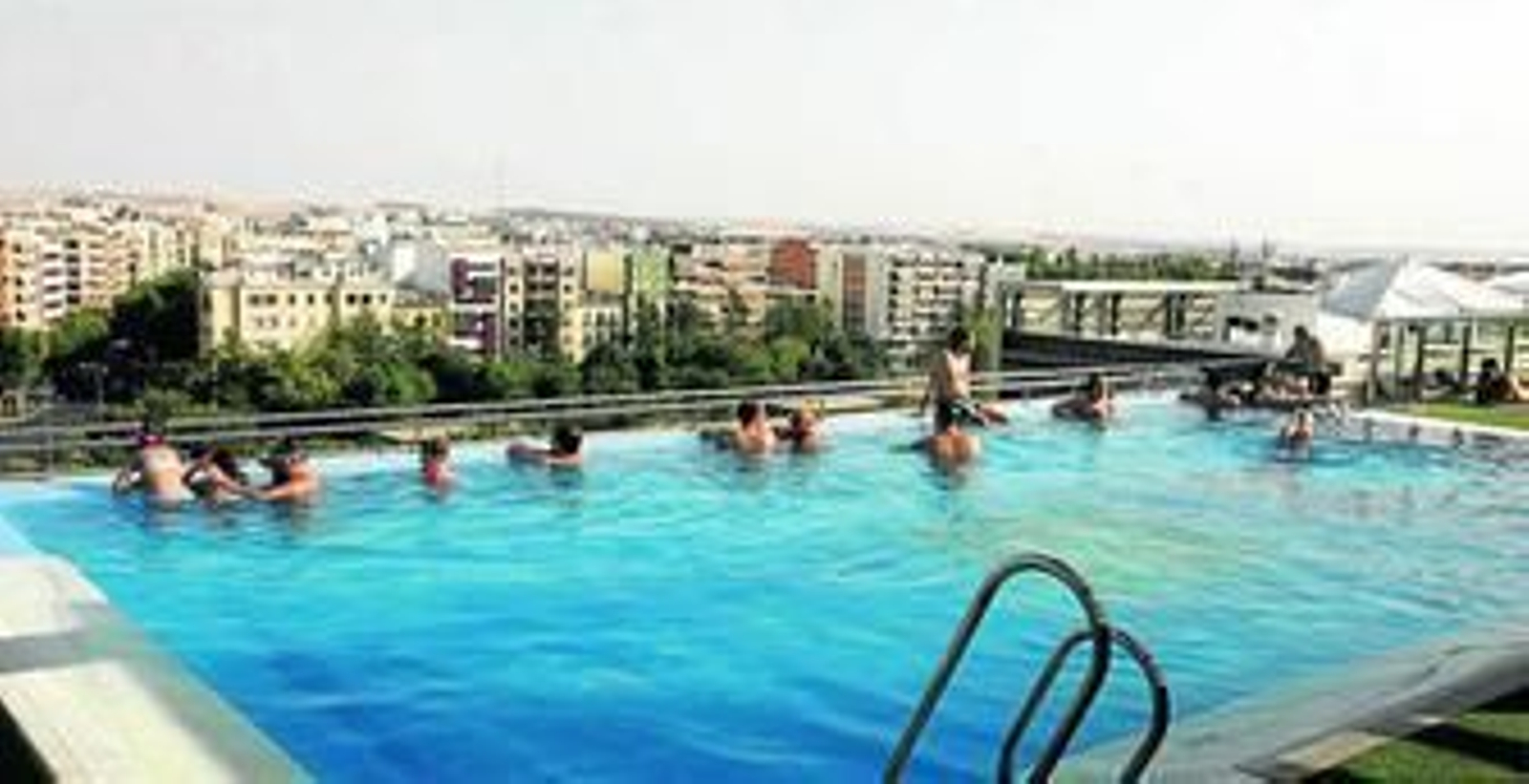 Varios clientes del hotel Córdoba Center se refrescan en la piscina del hotel al tiempo que disfrutan de las vistas de la terraza.