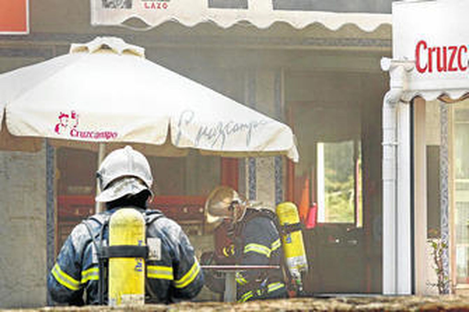Operarios de los bomberos actúan en el local siniestrado.