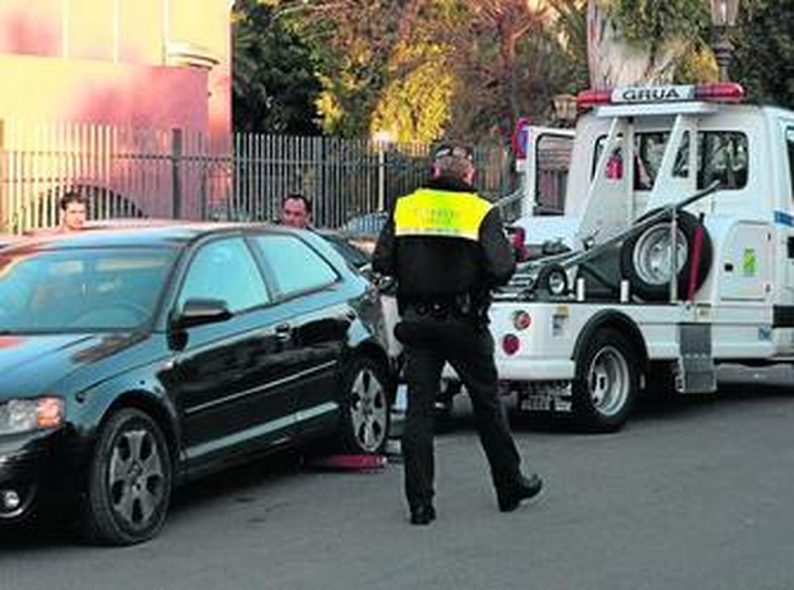 La grúa retira un vehículo mal estacionado en presencia de un agente de la Policía Local.