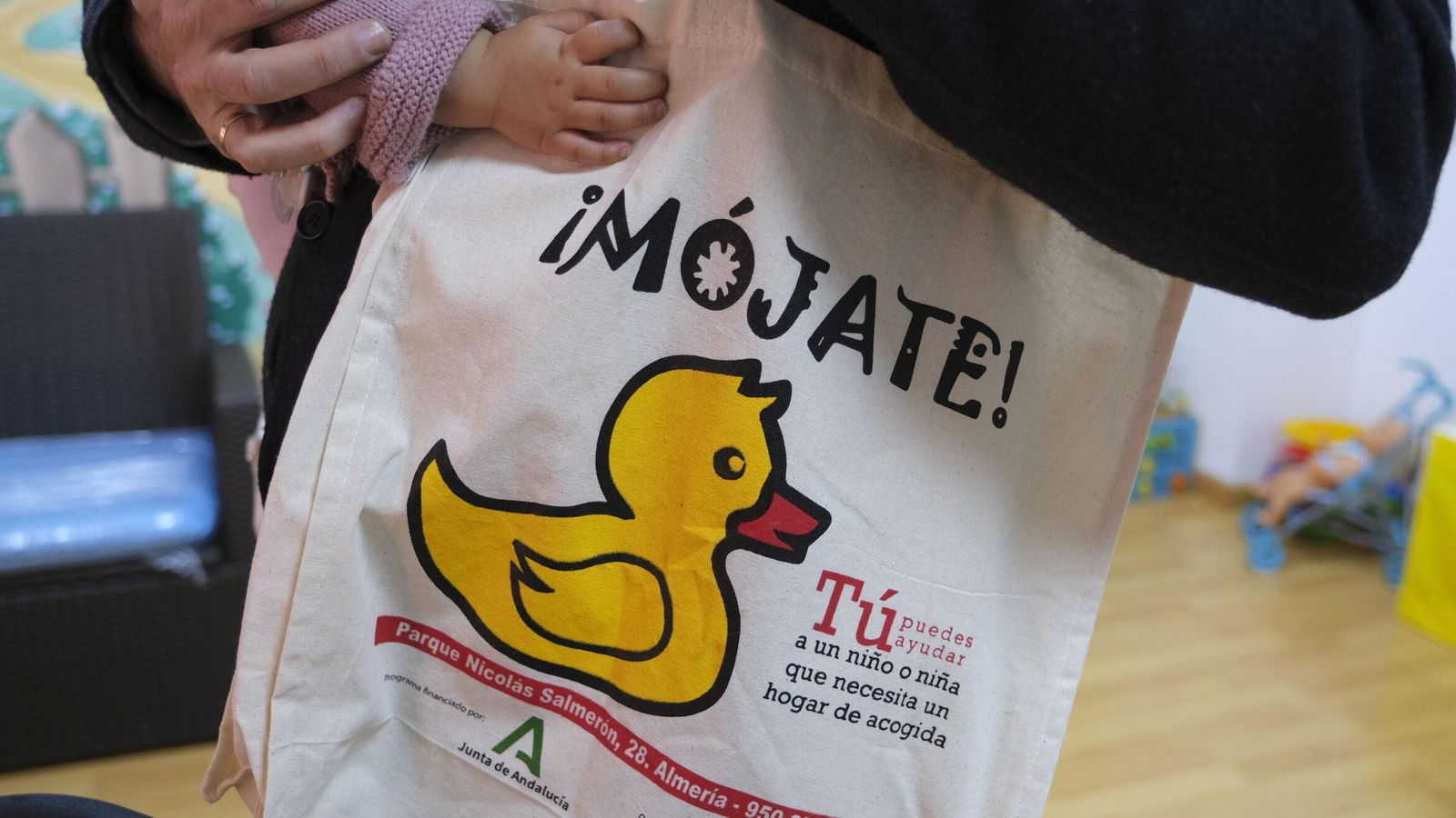 Carlos con su bebé en brazos lleva la bolsa con el lema de la campaña de Acogimiento.