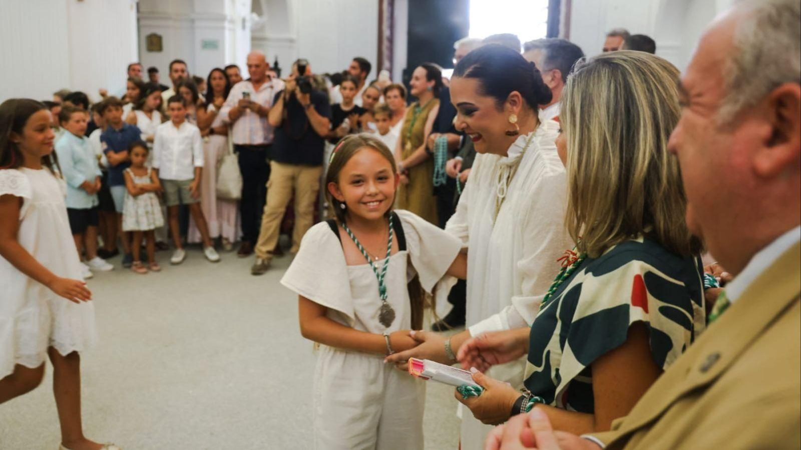Una joven rociera recibe su medalla de la Virgen.