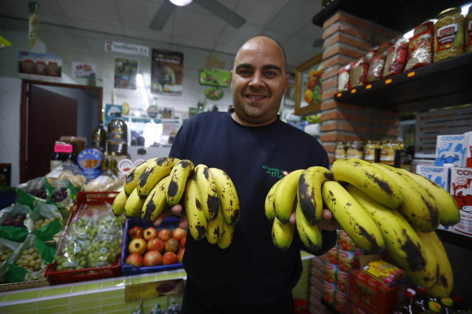 Un frutero cordobés muestra dos piñas de plátanos.